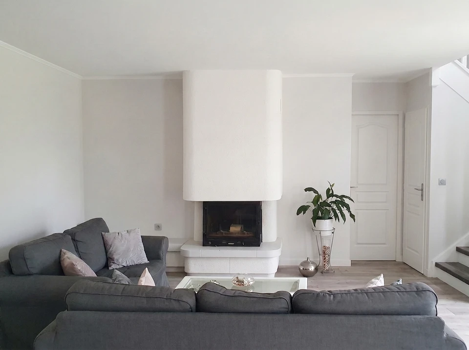 Salon contemporain avec cheminée encastrée à foyer fermé, habillage en enduit blanc texturé avec hood arrondie
