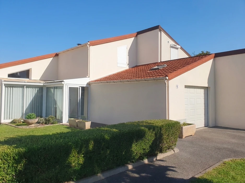 Maison individuelle de plain-pied avec étage partiel, façade enduit beige, toiture tuiles canal terre cuite