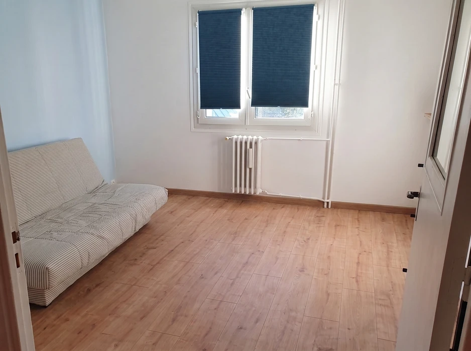 Pièce vide lumineuse avec parquet stratifié chêne clair, mur blanc