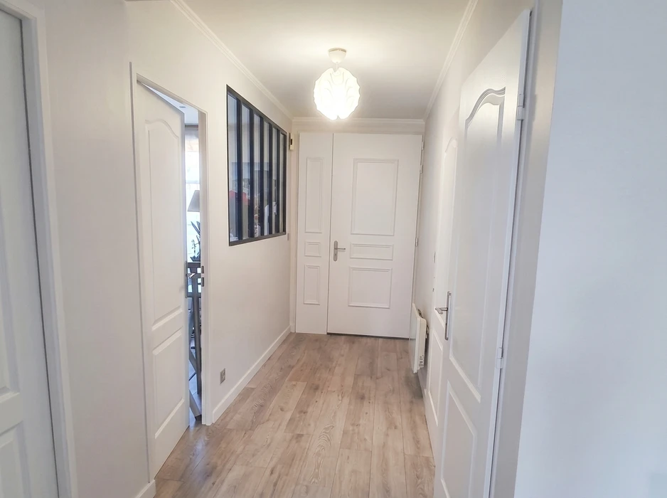 Couloir d'appartement rénové, lumineux, avec parquet stratifié chêne clair